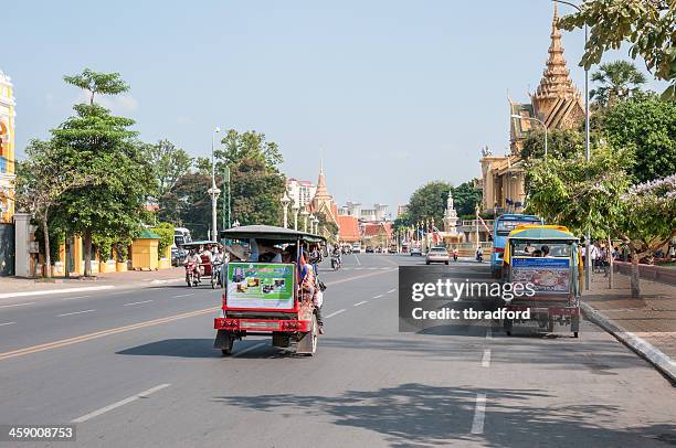 tuktuks driving passed the royal palace in phnom penh - phnom penh stock pictures, royalty-free photos & images