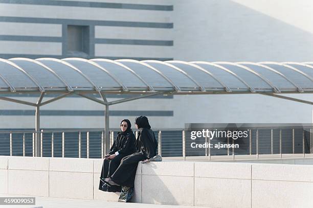 two women sitting infront museum of islamic art in doha - doha museum stock pictures, royalty-free photos & images