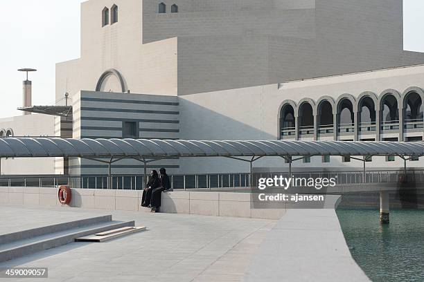 two women sitting infront museum of islamic art in doha - doha museum stock pictures, royalty-free photos & images