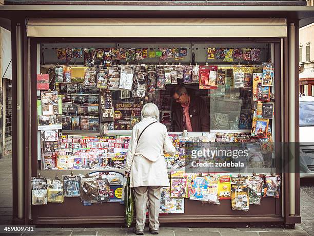 elder woman buying magazine at italian news stand - krantenkiosk stockfoto's en -beelden