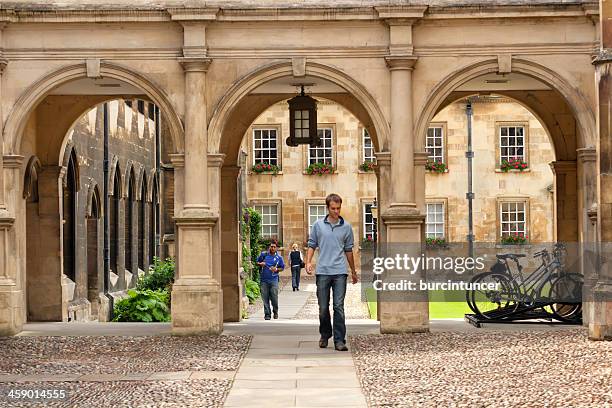 students passing through a college campus gate in cambridge university - trinity college cambridge stock pictures, royalty-free photos & images