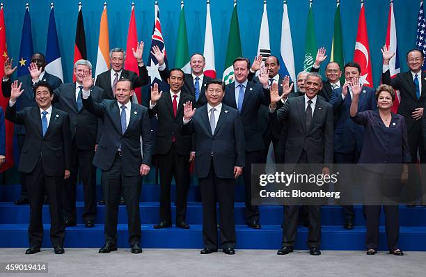 World leaders and delegates wave as they pose for a family photograph at the Group of 20 summit in Brisbane, Australia, on Saturday, Nov. 15, 2014....