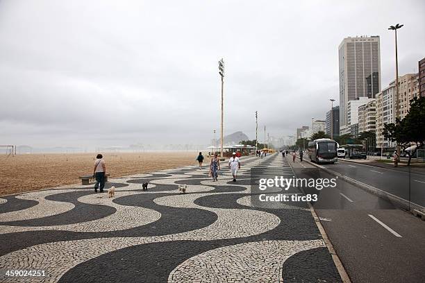 people on the seafront walkway at copacabana beach - rio de janeiro skyline stock pictures, royalty-free photos & images