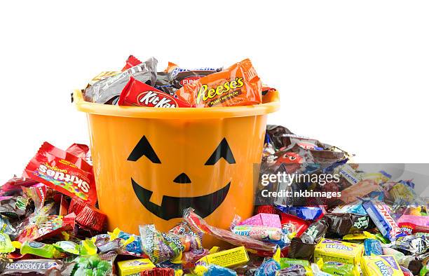 orange plastic halloween bucket filled and overflowing with candy - confectionery stock pictures, royalty-free photos & images