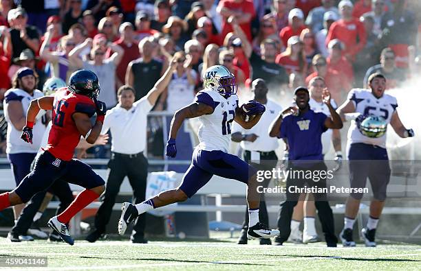 Running back Dwayne Washington of the Washington Huskies rushes the football en route to scoring on a 66 yard touchdown past safety Jourdon Grandon...