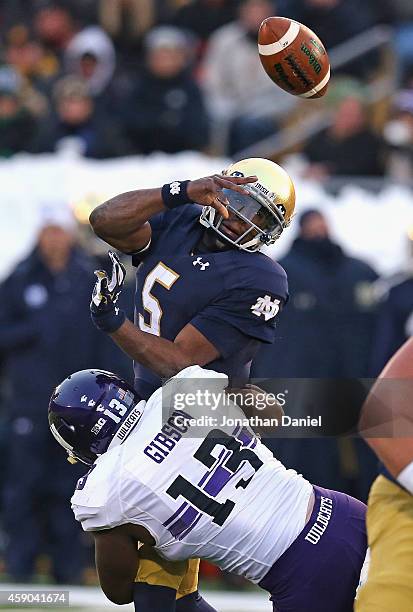 Everett Golson of the Notre Dame Fighting Irish is hit by Deonte Gibson 13 of the Northwestern Wildcats forcing a turnover at Notre Dame Stadium on...