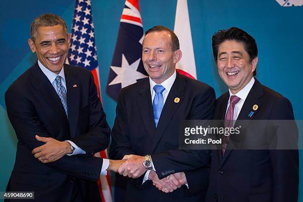 President Barack Obama, Australian Prime Minister Tony Abbott, and Japan's Prime Minister Shinzo Abe shake hands during a trilateral meeting at the...