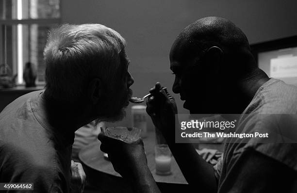 Caretaker Phillip Gant, right, feeds Stephen Lee his medicine which he mixed into apple sauce, May 28, 2014 in Washington, DC. Stephen is suffering...