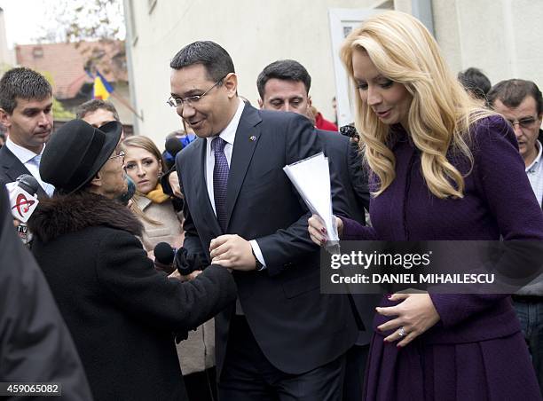 Romanian Prime Minister and presidential candidate Victor Ponta and his wife Daciana Sarbu are greeted by a supporter after voting at a polling...