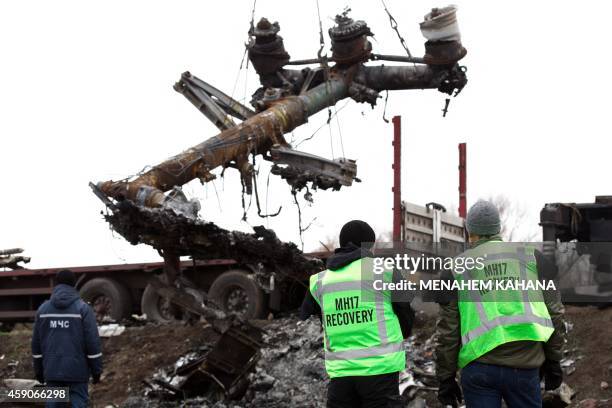 Members of the Dutch expert team watch as parts of the wreckage of the Malaysia Airlines Flight MH17 are removed and loaded on a truck at the crash...