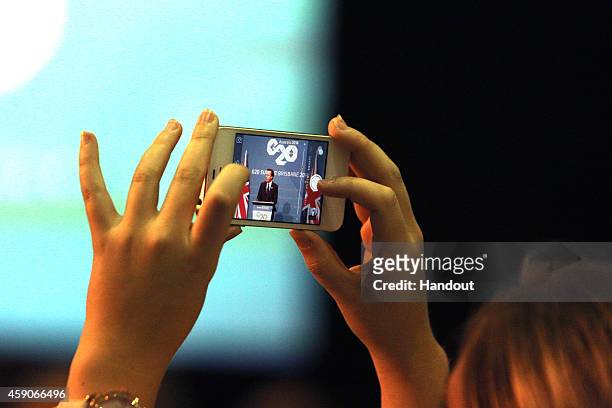 In this handout photo provided by the G20 Australia, United Kingdom's Prime Minister David Cameron is seen on a mobile phone as he addresses the...