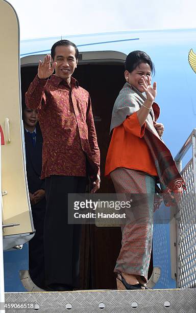 In this handout photo provided by the G20 Australia, Indonesia's President Joko Widodo and wife Iriana Widodo wave before departing Brisbane Airport...