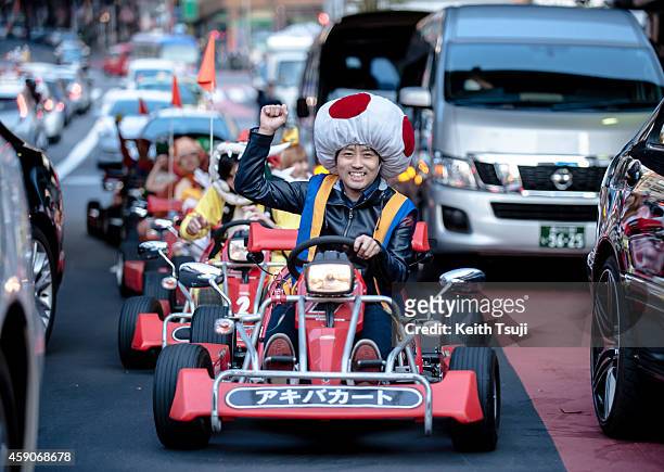 Participants drive around Tokyo in Mario Kart characters for the Real Mario Kart event in Tokyo on November 16, 2014 in Tokyo, Japan. The organizer...