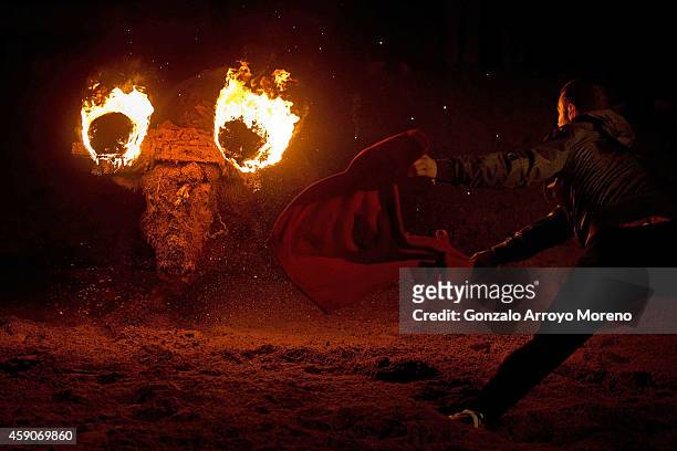 Reveler uses a jersey as a cape ahead of a bull with flammable balls attached to it's horns during the 'Toro de Jubilo' fire bull festival on...