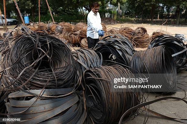 Indian business owner, Niyazahmed Shaikh checks the quality of scrap steel strips at his factory in Viramgam, some 60 kms from Ahmedabad on November...