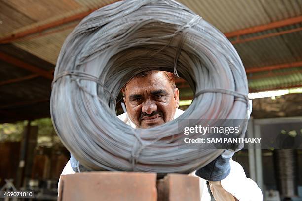 Indian owner of Bharat Industries, Niyazahmed Shaikh peers through coiled finished steel wires from scrap steel strips at his factory in Viramgam,...