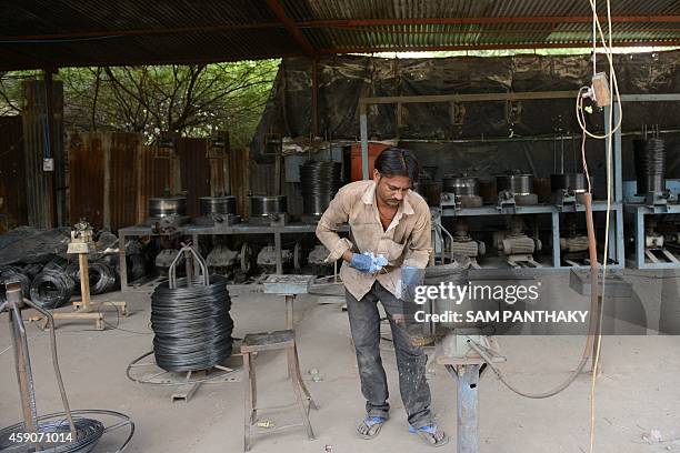 An Indian worker prepares steel wires from scrap steel strips at his factory in Viramgam, some 60 kms from Ahmedabad on November 16, 2014. Bharat...