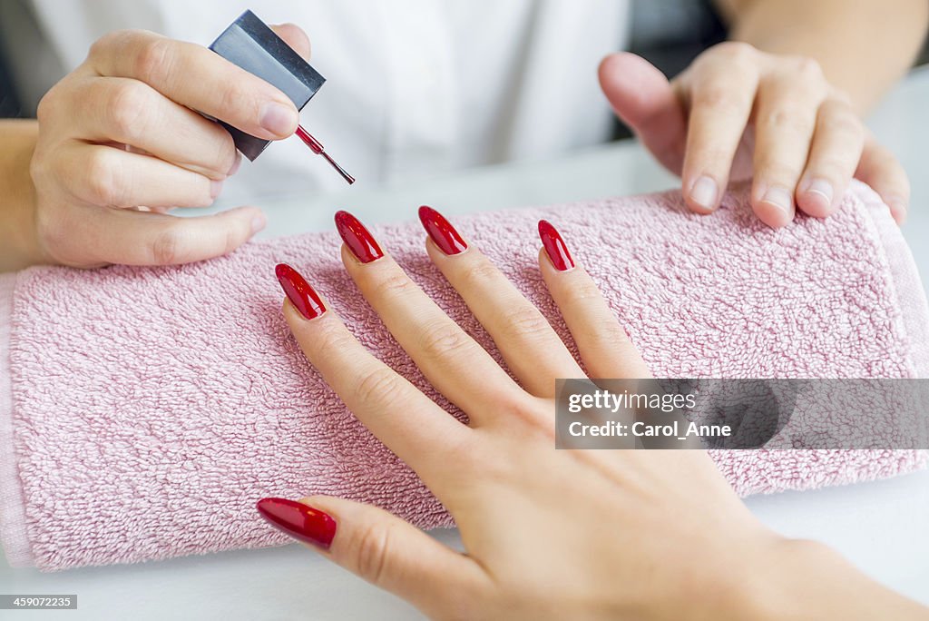 A woman with red painted nails getting a manicure