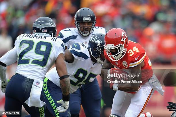 Knile Davis of the Kansas City Chiefs runs the ball against Earl Thomas and Demarcus Dobbs of the Seattle Seahawks during the first quarter at...