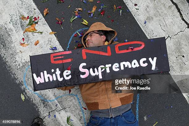 Demonstrator holds a sign that reads, " End White Supremacy", as he lays on the ground during a protest of the shooting death of Michael Brown by a...