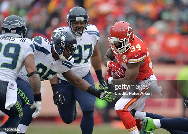 Knile Davis of the Kansas City Chiefs runs the ball against Demarcus Dobbs and Earl Thomas of the Seattle Seahawks during the game at Arrowhead...
