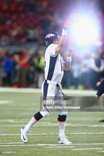 Peyton Manning of the Denver Broncos passes during warm-ups as a camera flash lights up in the background prior to playing against the St. Louis Rams...