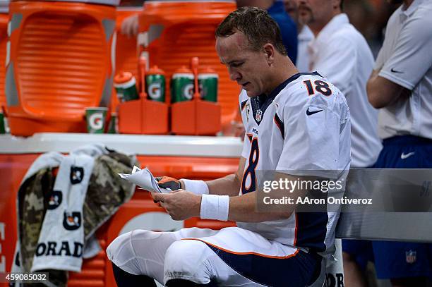 Peyton Manning of the Denver Broncos reads the playbook after failing to get a drive going against he St. Louis Rams during the second half of the...