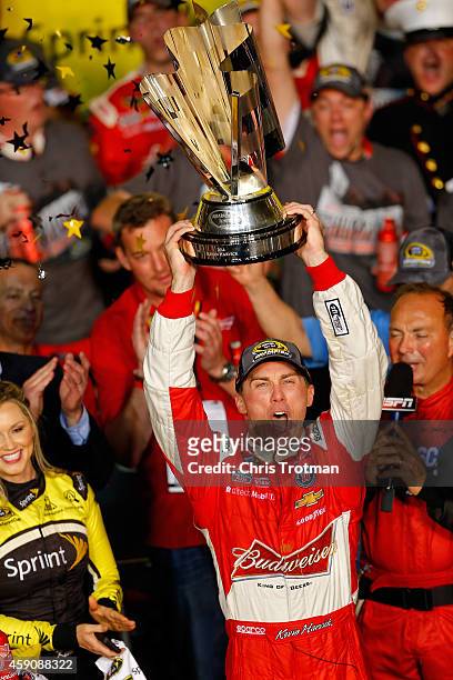 Kevin Harvick, driver of the Budweiser Chevrolet, celebrates with the trophy in Victory Lane after winning the NASCAR Sprint Cup Series Ford EcoBoost...
