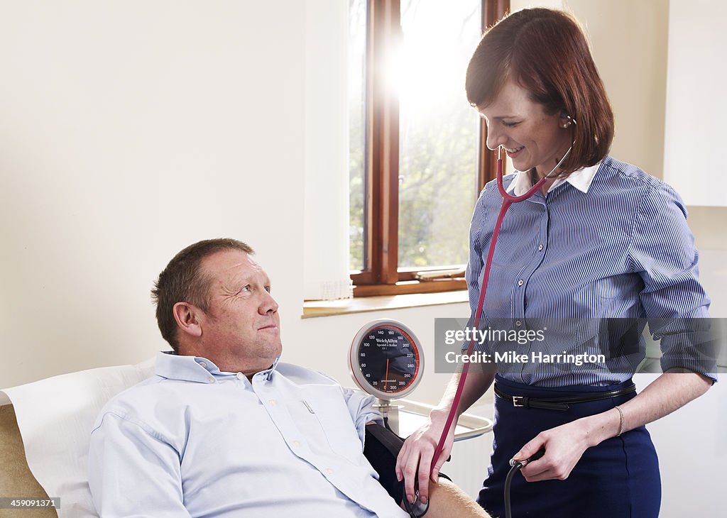 GP measuring blood pressure of patient in surgery.