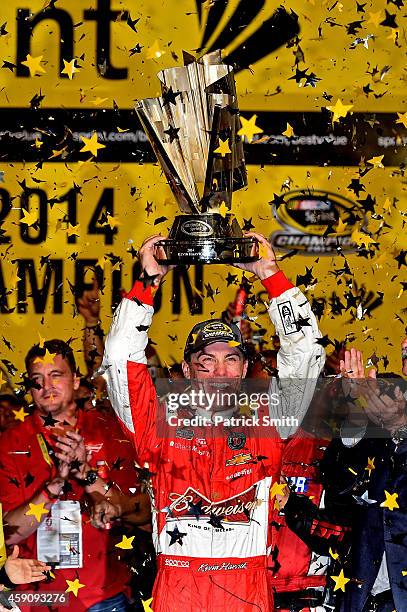 Kevin Harvick, driver of the Budweiser Chevrolet, celebrates with the trophy in victory lane after winning during the NASCAR Sprint Cup Series Ford...