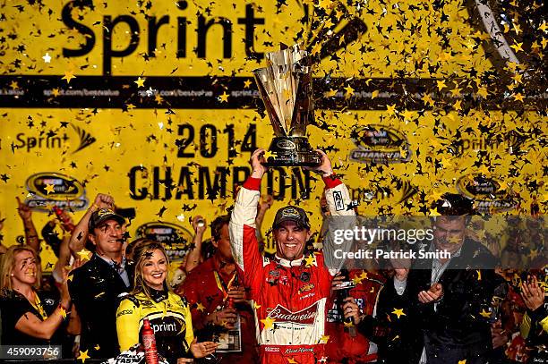 Kevin Harvick, driver of the Budweiser Chevrolet, celebrates with the trophy in victory lane after winning during the NASCAR Sprint Cup Series Ford...