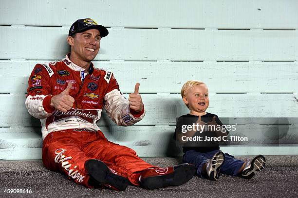 Kevin Harvick, driver of the Budweiser Chevrolet, sits with his son Keelan on the track after winning the NASCAR Sprint Cup Series championship and...