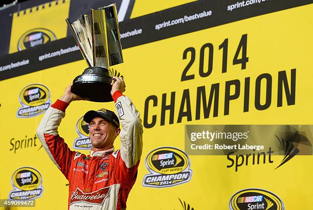 Kevin Harvick, driver of the Budweiser Chevrolet, celebrates with the trophy in victory lane after winning the NASCAR Sprint Cup Series Ford EcoBoost...