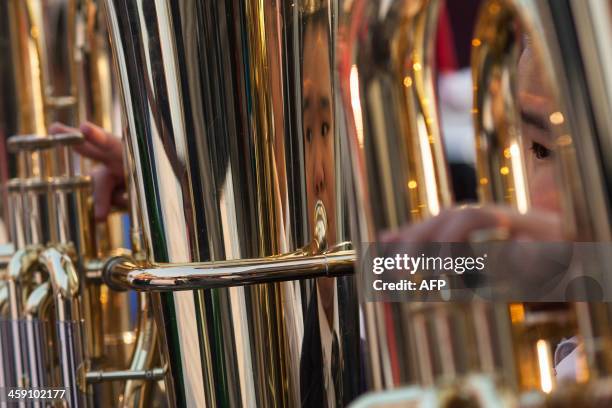 Young boy is reflected in his instrument as he plays Christmas songs with an orchestra in Hong Kong on December 23, 2013. Christmas is celebrated...