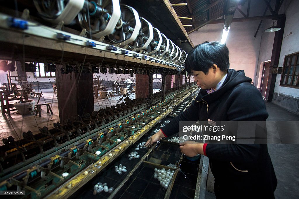 A woman is working on a mechanic silk reeling streamline.