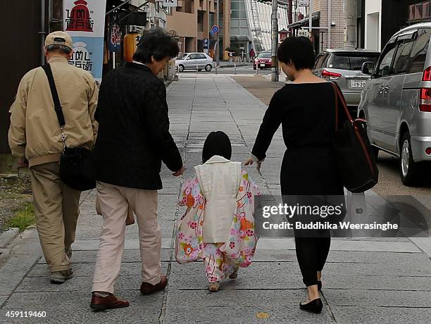 Three-year-old girl dressed in traditional kimono costume walks to the Shosha Shrine with her parents during the Shichi-Go-San Festival on November...