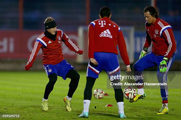 Bastian Schweinsteiger of Bayern Muenchen battles for the ball with his team mates Heinz Mueller and Medhi Benatia during a training session at...