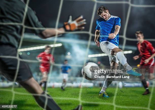 soccer player kicking ball at goal - fußball spielball stock-fotos und bilder