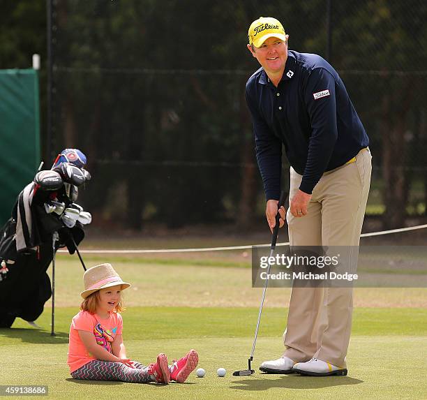 Jarrod Lyle of Australia putts on the practice green with daughter Lucy Lyle watching ahead of the 2014 Australian Masters at The Metropolitan Golf...