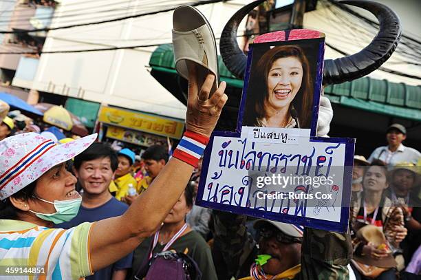 An anti-government protester uses a shoe to hit an image of Thai Prime Minister Yingluck Shinawatra outside a besieged police station near the venue...