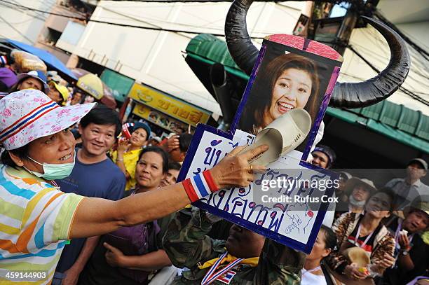 An anti-government protester uses a shoe to hit an image of Thai Prime Minister Yingluck Shinawatra outside a besieged police station near the venue...