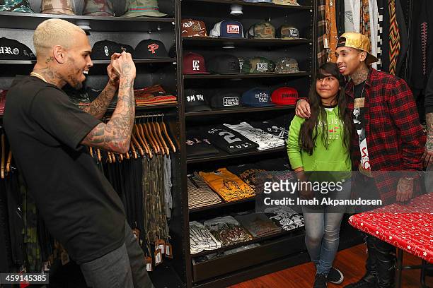 Singer Chris Brown takes a photograph of a fan posing with rapper Tyga at the 1st Annual Xmas Toy Drive hosted by Chris Brown and Brooklyn Projects...