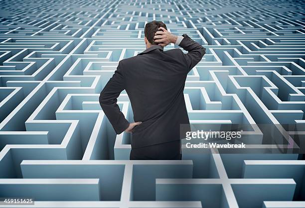 back of businessman getting lost in a maze - problemen stockfoto's en -beelden
