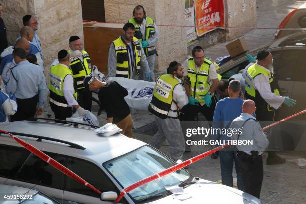 Israeli Zaka emergency services volunteers carry the body of a Palestinian assailant who was shot dead while attacking a synagogue in the...