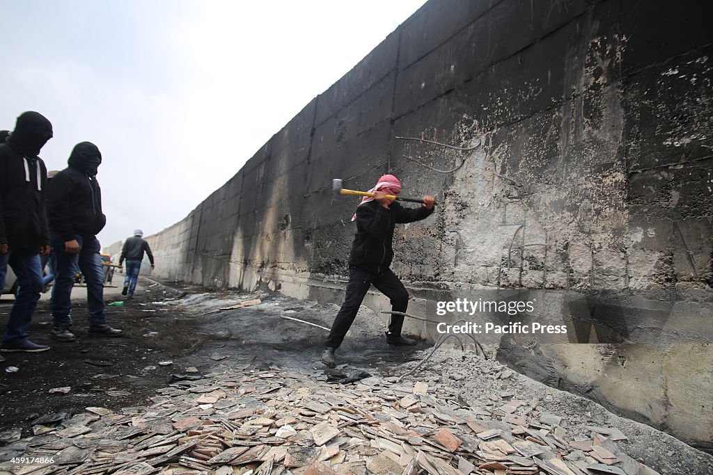 Palestinians trying to tear down the wall in the town of Abu...