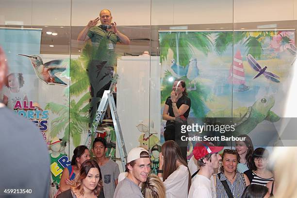 Workers inside of a shop attempt to gain a glimpse as Kim Kardashian arrives to promote her new fragrance "Fleur Fatale" at Chadstone Shopping Centre...