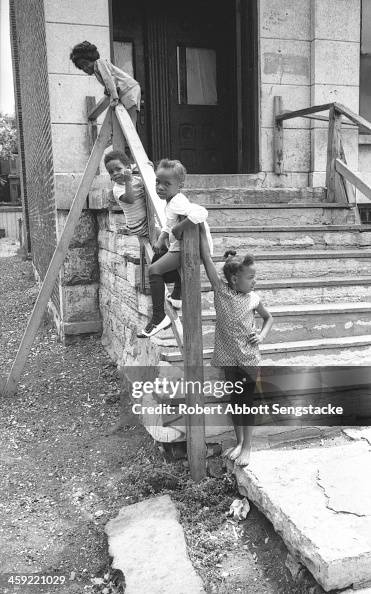 Child Stooping A group of young children sit and gather on the stoop of an apartment ...