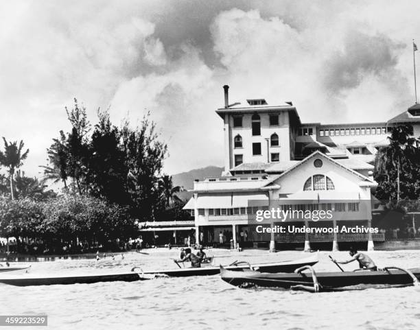 Swimming star Duke Kahanamoku wins the one man canoe championship in his long black and white outrigger, crossing the finish line in front of the...