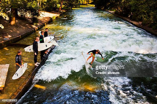 woman surfing in the eisbach river munich germany - englischer garten stock pictures, royalty-free photos & images
