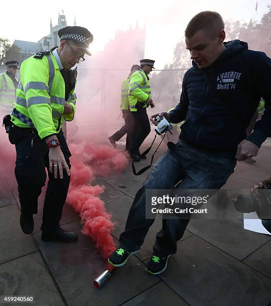 Protester kicks a smoke canister away from a police officer during a demonstration against fees and cuts in the education system on November 19, 2014...